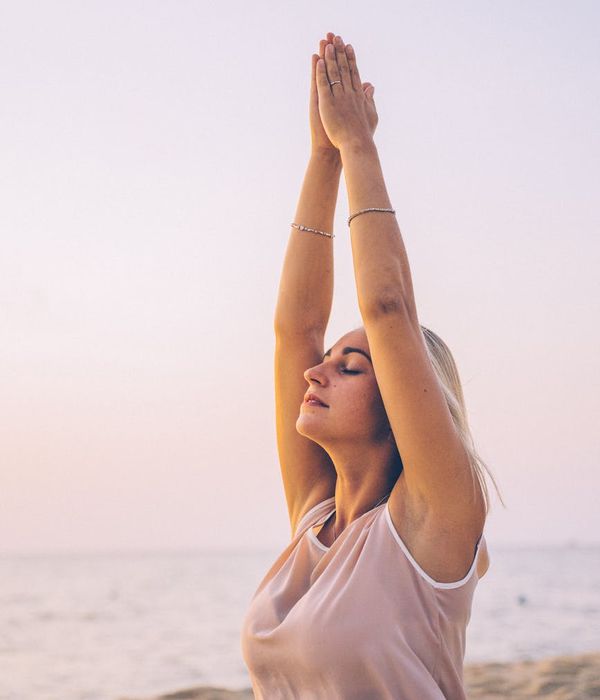 Person meditating peacefully outdoors at sunrise.